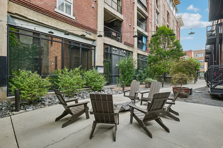 Outdoor patio space featuring concrete flooring, a central fire pit, and surrounding Adirondack chairs