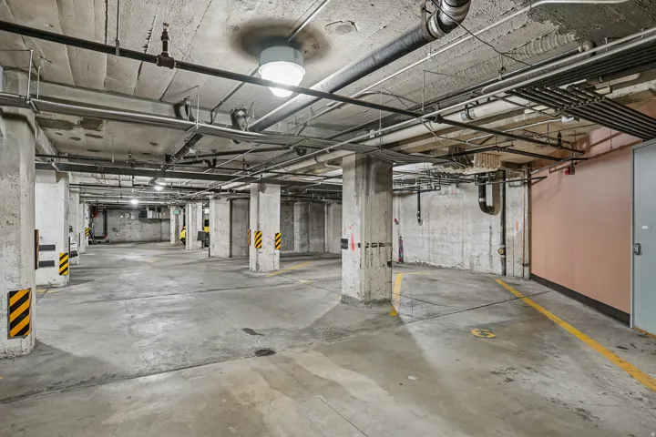 Underground parking garage featuring concrete flooring and exposed ceiling infrastructure