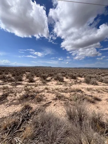 Expansive desert landscape featuring arid terrain and native shrubs under a partly cloudy sky