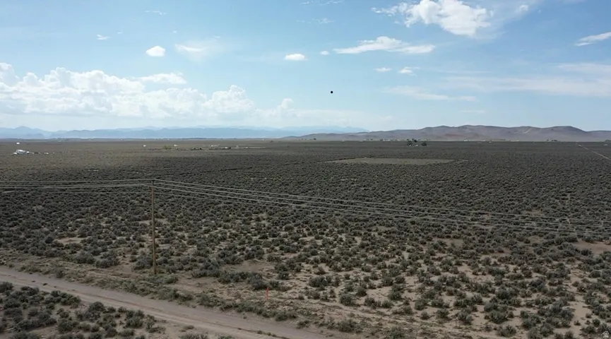 Expansive land parcel featuring natural desert vegetation, a dirt road, and utility poles with overhead lines