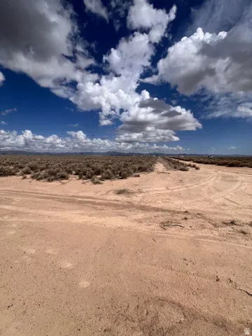 Expansive undeveloped land featuring arid ground cover and a vast open sky
