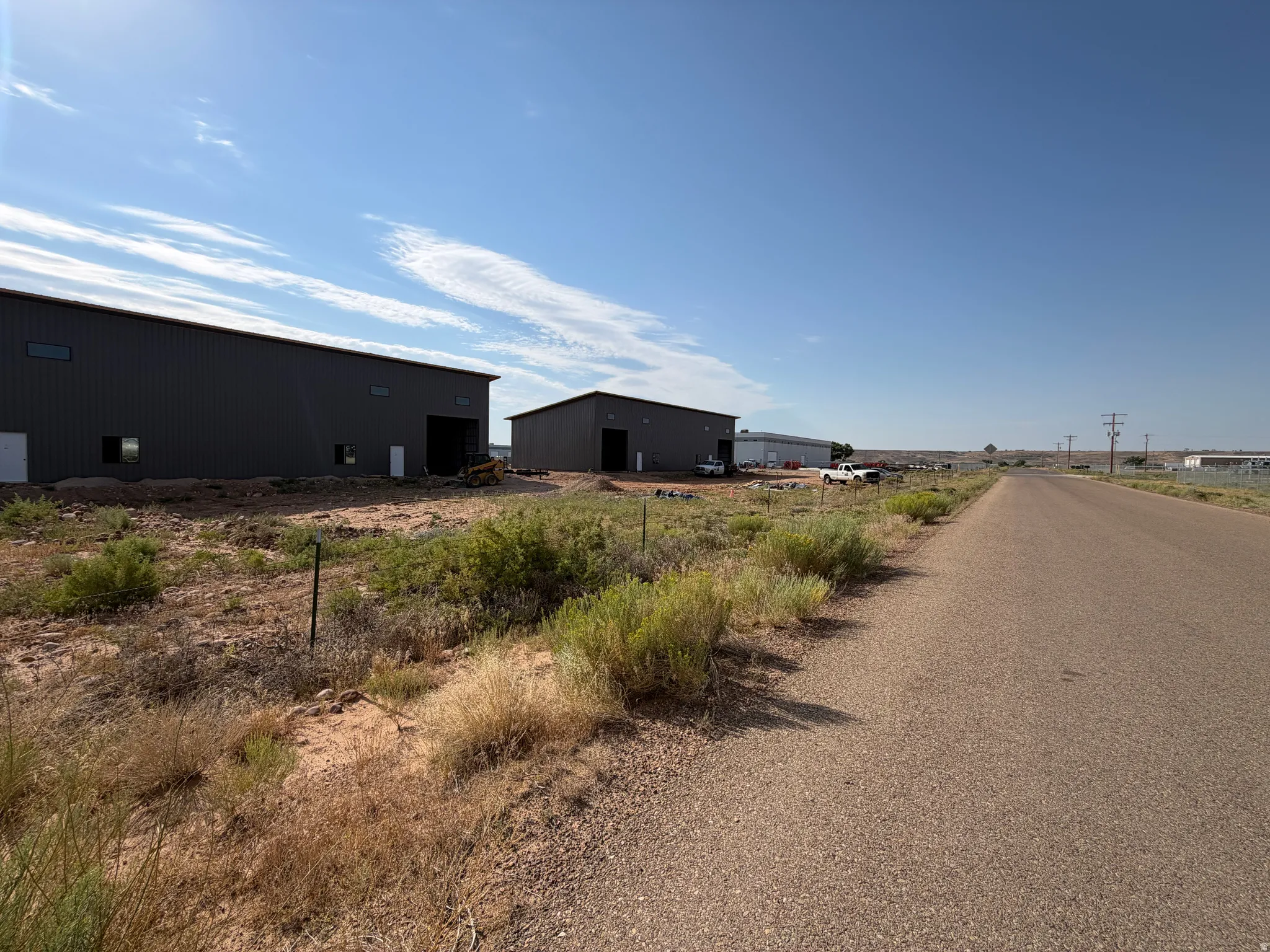 Two large commercial buildings with corrugated metal siding, multiple entry points, and a gravel road frontage