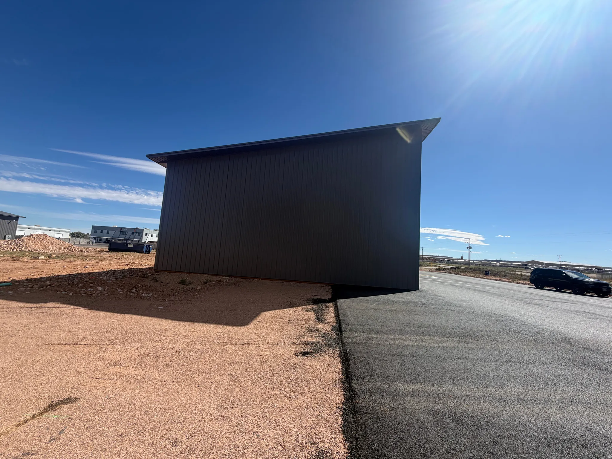 Structure with dark panel siding and a sloped roofline