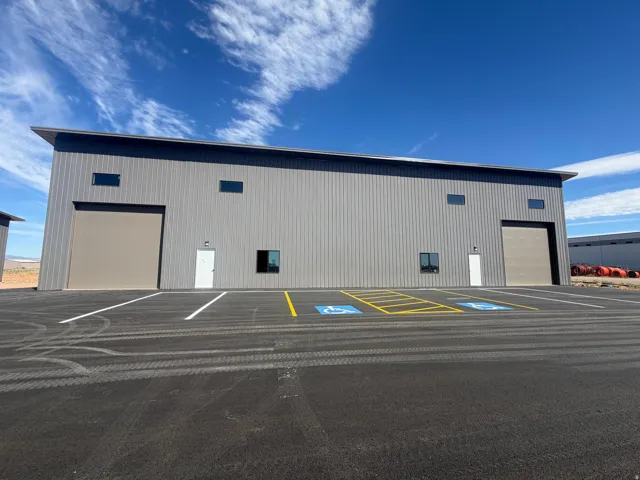 Metal-sided commercial building with multiple roll-up doors, various windows, and dedicated parking