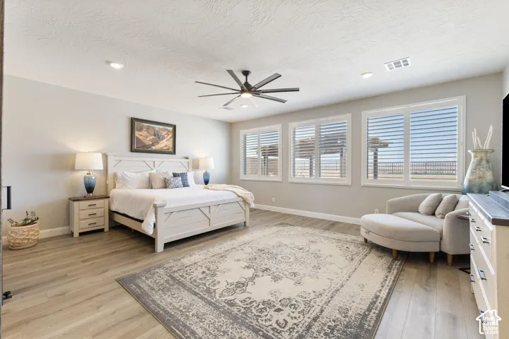 Spacious bedroom featuring wood-finish flooring, recessed lighting, and a ceiling fan