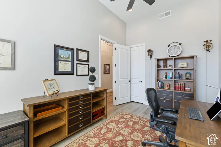 Workspace featuring vaulted ceilings, wood-finish flooring, a ceiling fan, and built-in double doors