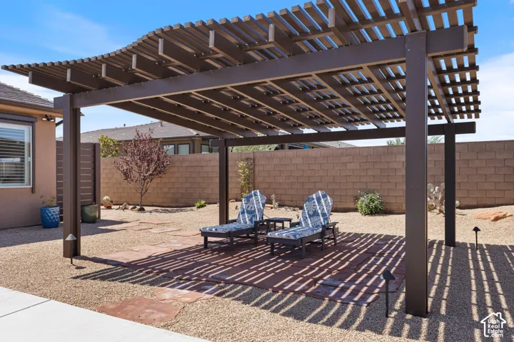Expansive backyard featuring a large brown pergola providing shaded patio space on a flagstone pad