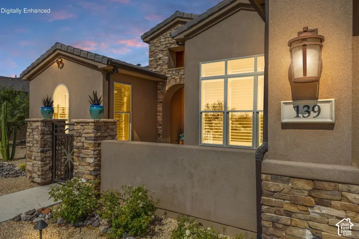 Exterior facade featuring a stucco finish with stone accents, a tiled roof, and an arched entry
