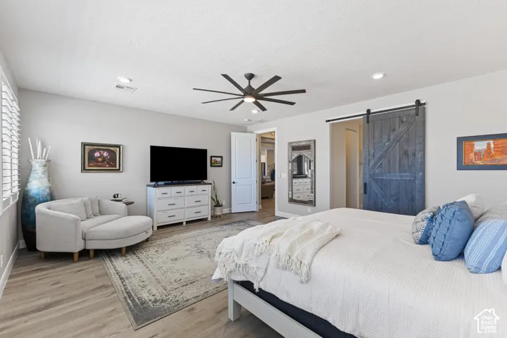Spacious room featuring wood-finish flooring, a contemporary ceiling fan, and a rustic-style barn door