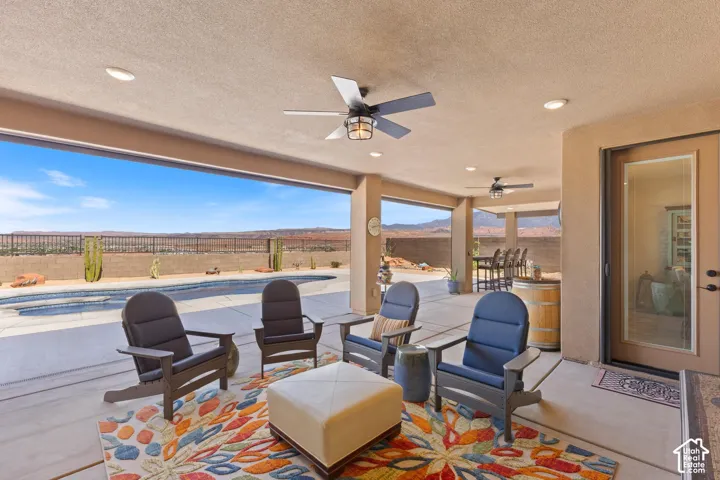 Expansive covered patio featuring multiple ceiling fans, recessed lighting, and direct access to an outdoor swimming pool