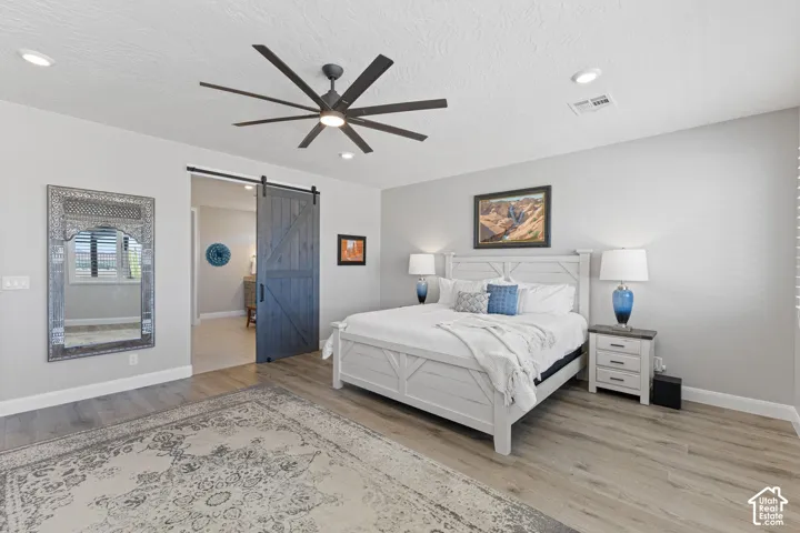 Spacious sleeping area featuring wood-finish flooring, a modern ceiling fan, and recessed lighting