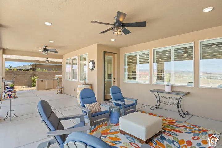 Expansive covered patio featuring multiple ceiling fans, recessed lighting, and a built-in outdoor kitchen with a stone-finish countertop