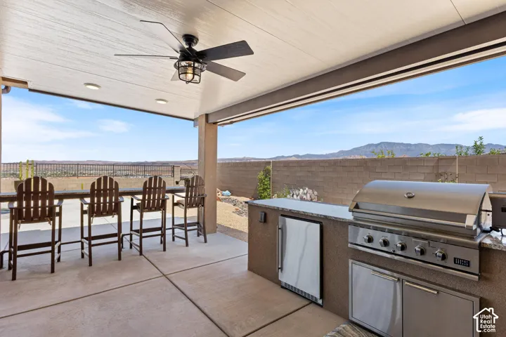 Covered patio featuring an outdoor kitchen with built-in stainless steel grill and refrigerator