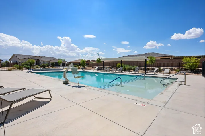 Resort-style swimming pool featuring integrated steps, handrails, and surrounding concrete decking