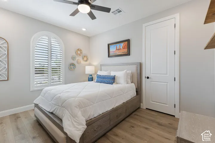 Arched window with plantation shutters, wood-finish flooring, recessed lighting, ceiling fan, and a paneled interior door