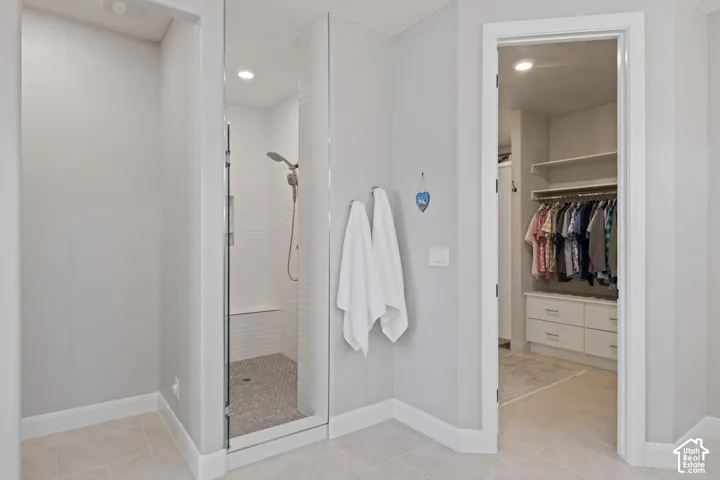 Glass-enclosed shower featuring a tiled bench and pebble-finish floor