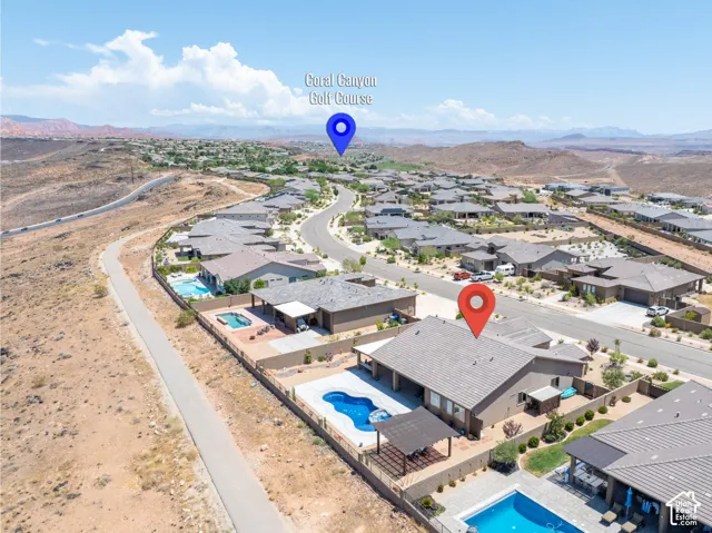 Aerial perspective highlighting a residential community with numerous single-story properties featuring swimming pools and paved driveways