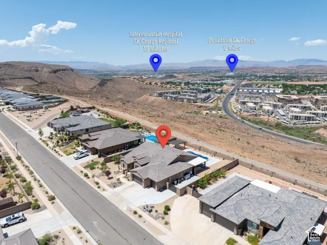 Aerial perspective showcasing a single-story residence with a pool, a multi-car driveway, and a desert-adapted landscape