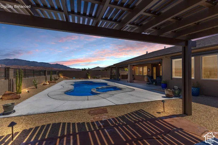 Expansive outdoor living area featuring a custom-shaped swimming pool, concrete decking, and desert landscaping