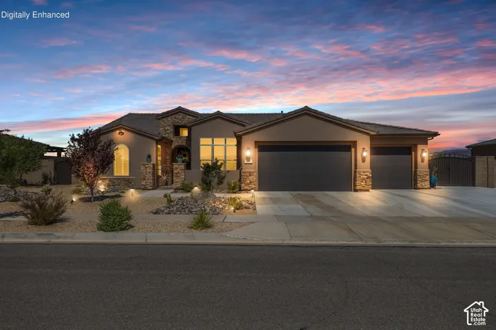 Stucco and stone facade home featuring a multi-car driveway with dual garage doors