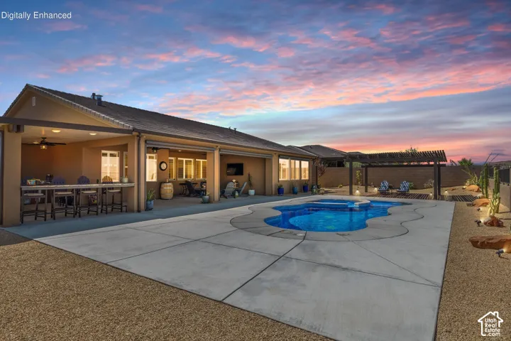 Expansive backyard featuring a freeform swimming pool with integrated spa, concrete decking, and desert landscaping