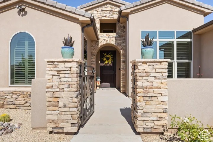 Stucco exterior featuring stacked stone accents, an arched entryway, and an ornamental iron gate