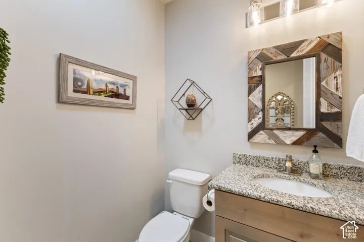 Granite countertop vanity with integrated sink, wood-finish cabinetry, and a decorative wood-framed mirror