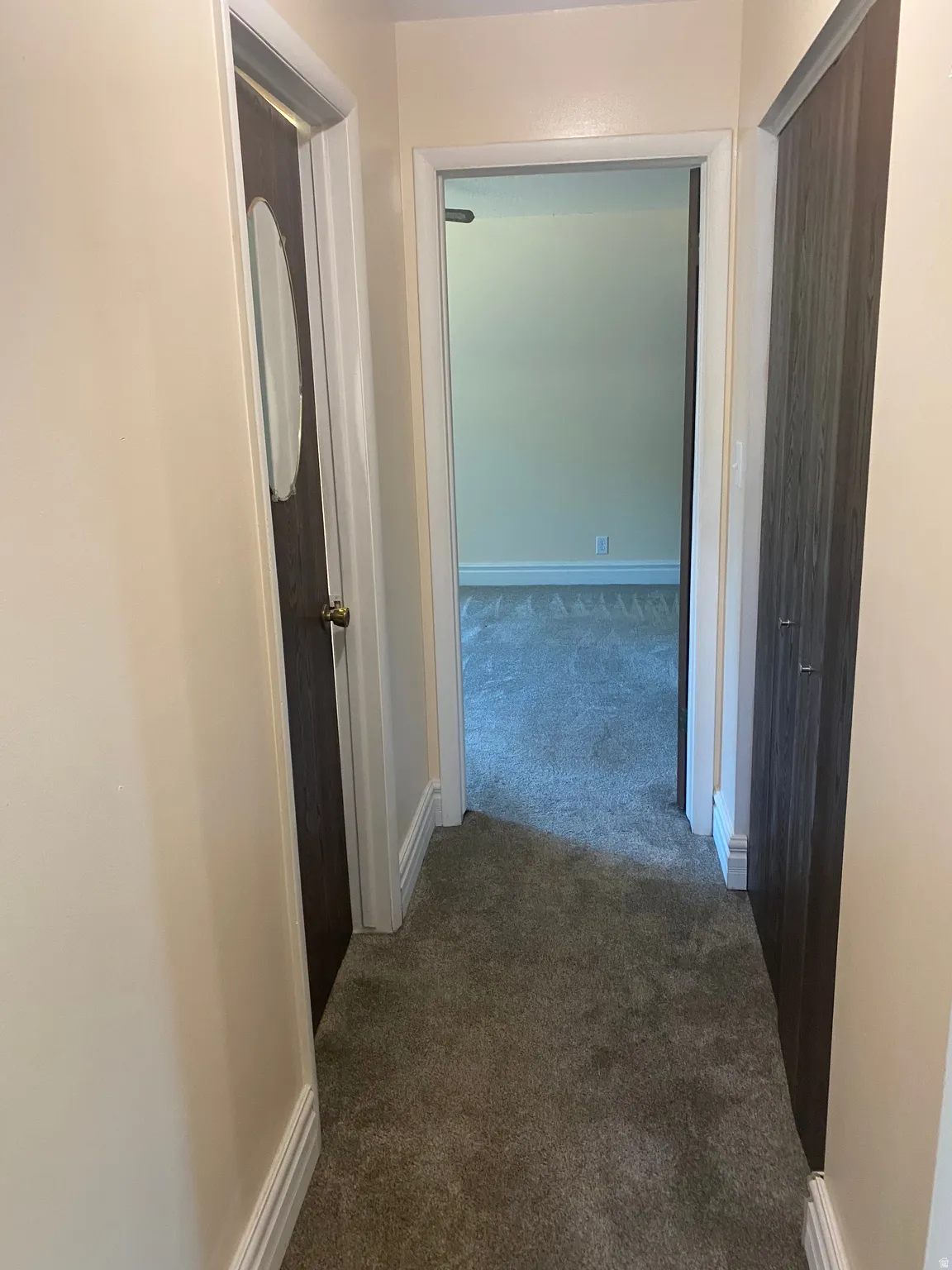 Hallway with plush gray carpeting and light beige wall paint