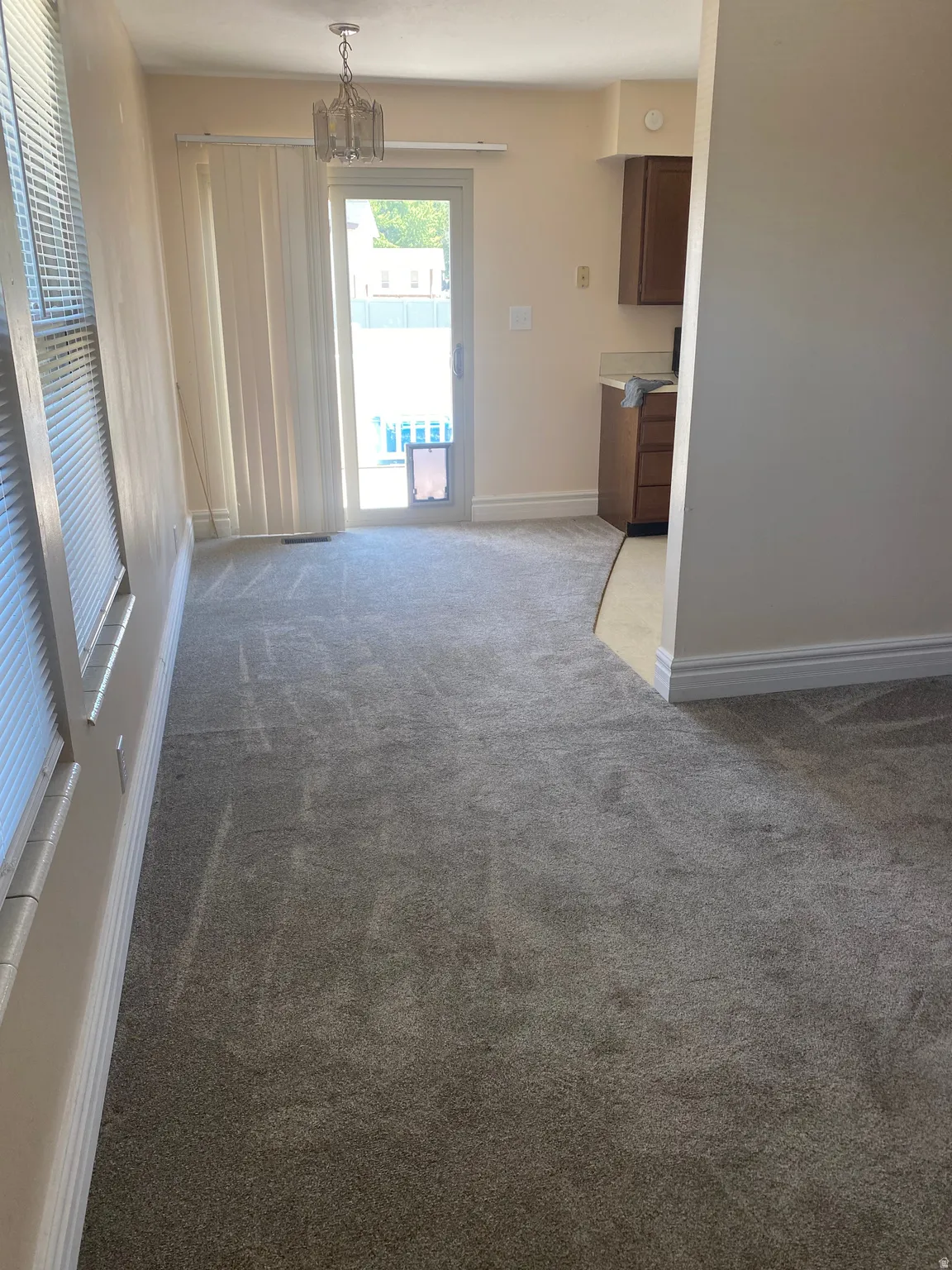 Carpeted room with a sliding glass door and vertical blinds