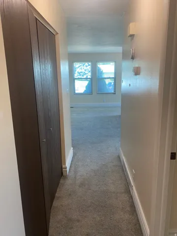 Hallway featuring plush grey carpeting and light-toned wall paint