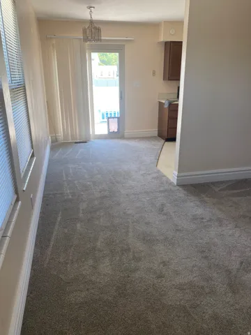 Carpeted room with a sliding glass door and vertical blinds