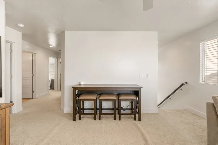 Carpeted floor plan featuring a hallway with white doors, recessed lighting, and a staircase with a black handrail and white balusters