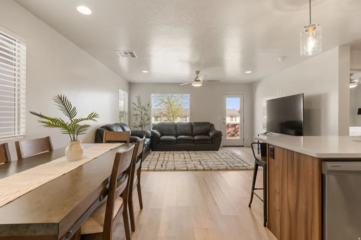 Open concept living and dining areas featuring wood-finish flooring, recessed lighting, and multiple windows with blinds