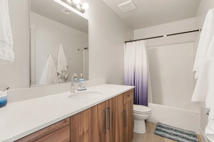 Bathroom featuring a wood-finish vanity with a white countertop and integrated sink, chrome faucet, and a large wall-mounted mirror