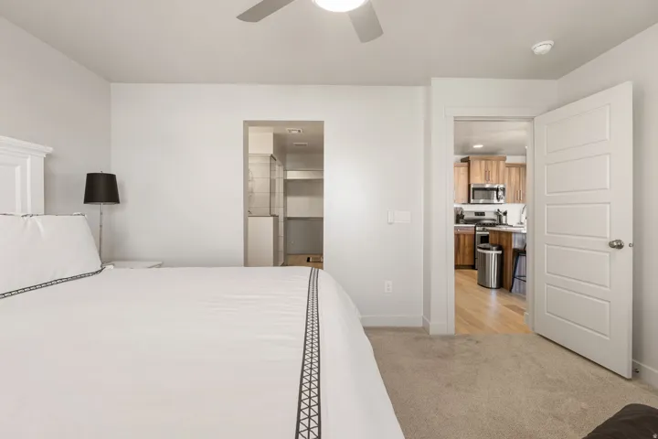 Carpeted sleeping area with light gray walls and a ceiling fan