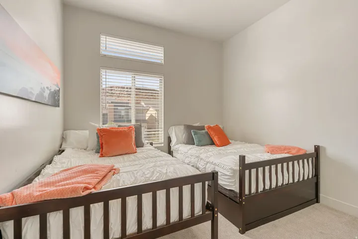 Bedroom featuring two dark wood bed frames, light grey carpet, and white walls