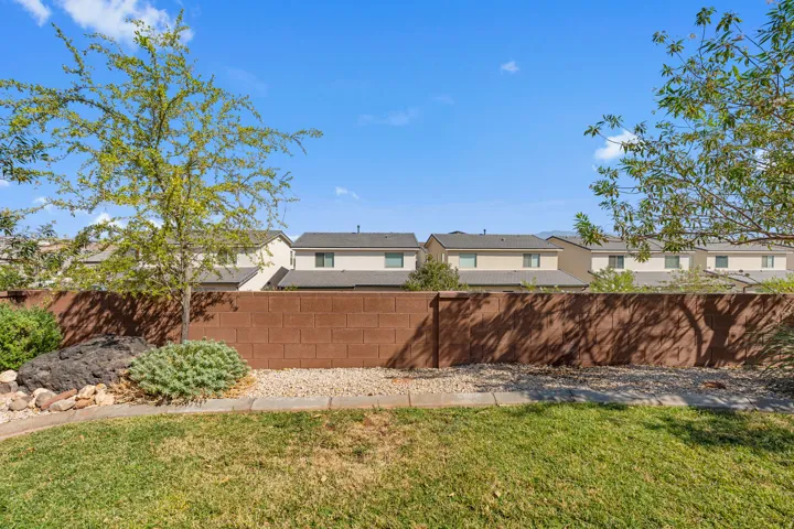 Private backyard space featuring a mature tree, established shrubbery, and a decorative rock border