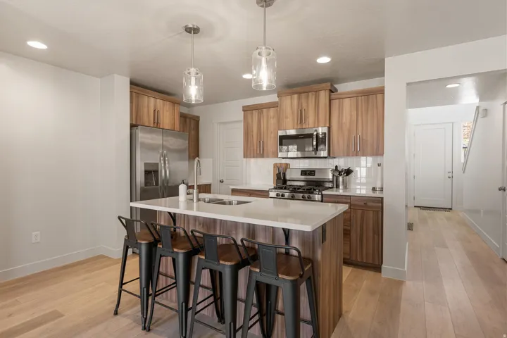 Kitchen featuring a central island with countertop seating, stainless steel appliances, wood-finish cabinetry, and recessed lighting