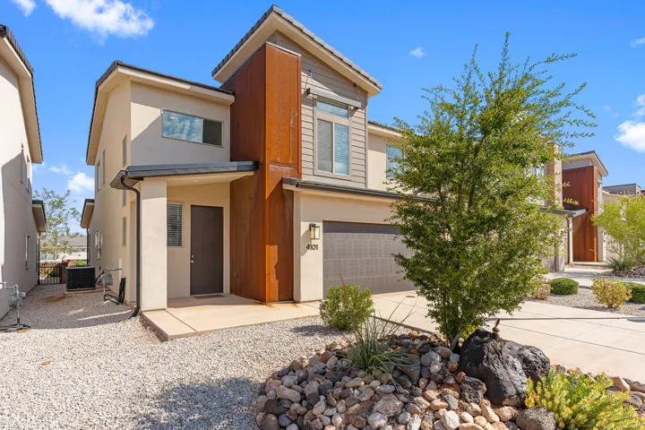 Contemporary multi-level residence featuring stucco and vertical siding with a prominent rust-toned architectural accent