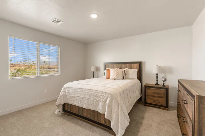 Carpeted bedroom featuring a large window with horizontal blinds, light neutral wall paint, and a ceiling-mounted recessed light