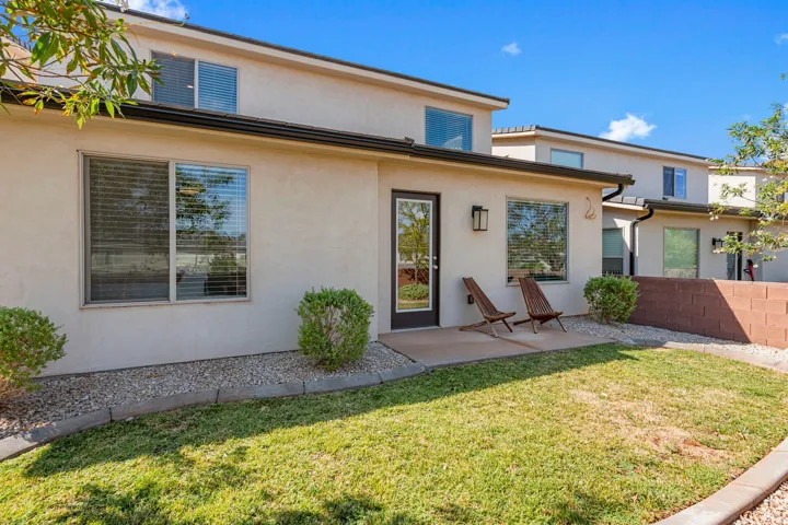 Rear exterior featuring a stucco facade, ground-level patio, full-light glass door, and an upper-level window