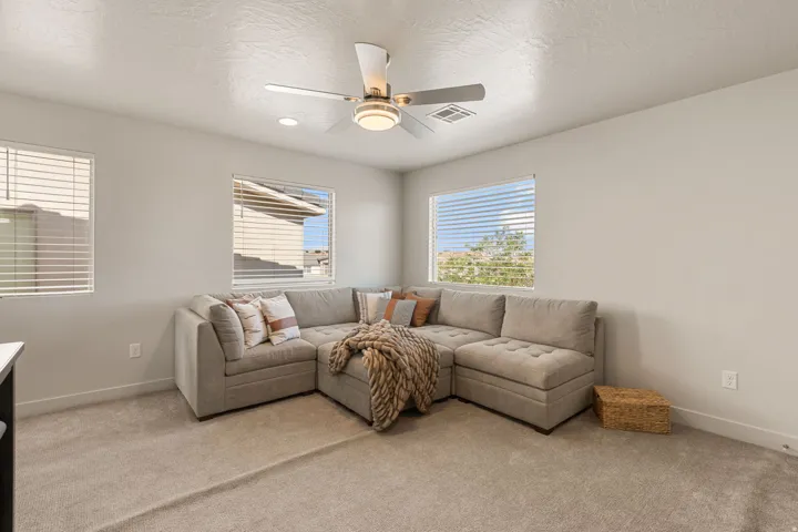 Carpeted room featuring multiple windows, recessed lighting, and a ceiling fan with integrated light