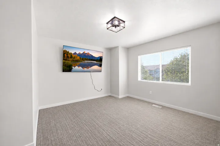 Spacious room featuring neutral wall tones and a window with horizontal blinds