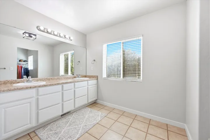 Double vanity with white cabinetry and a speckled countertop