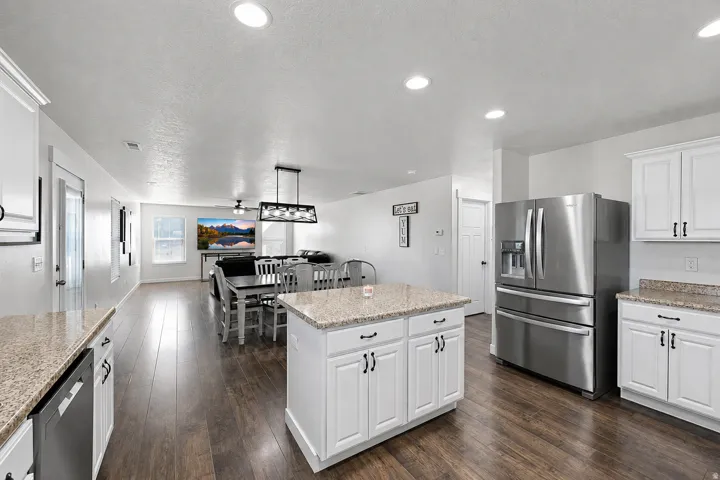 Open concept kitchen and living area featuring wood-finish flooring, recessed lighting, and white cabinetry