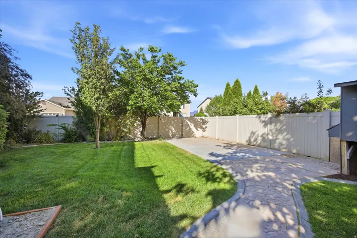 Expansive lawn area featuring a decorative stone-patterned pathway and a concrete driveway