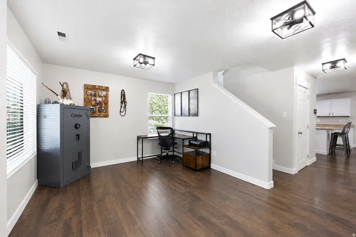 Spacious room featuring wood-finish flooring, light gray wall paint, and multiple windows with blinds