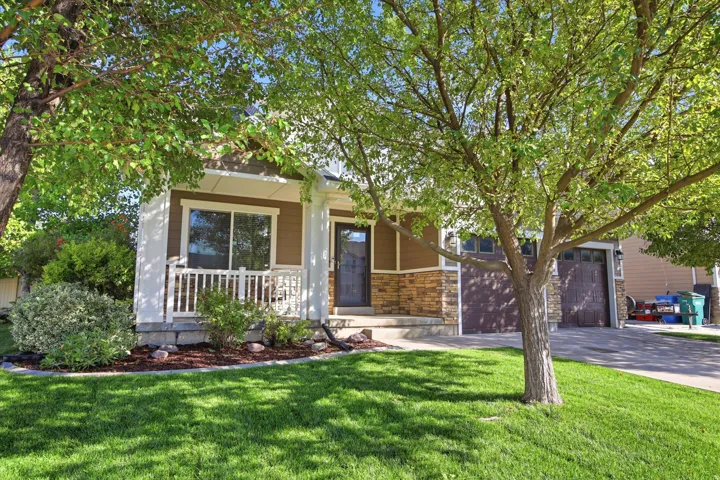 Exterior showcasing stacked stone accents, a covered front porch with white railings, and a dark entry door with a screen