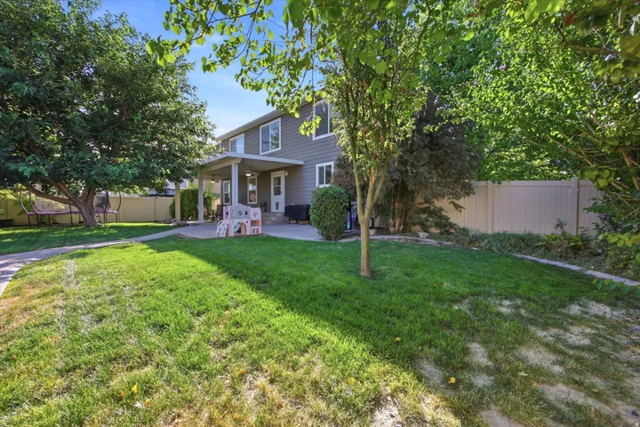 Expansive backyard with a manicured lawn, established trees, and a concrete patio