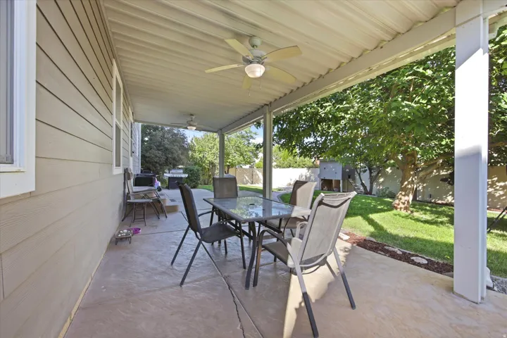 Covered patio featuring stamped concrete flooring, a corrugated metal ceiling, and two ceiling fans with integrated lighting